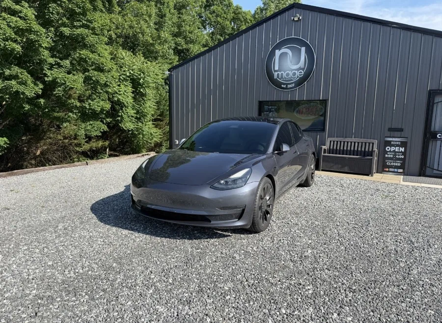 Gray Tesla Model 3 parked in front of the NU-Image building and sign