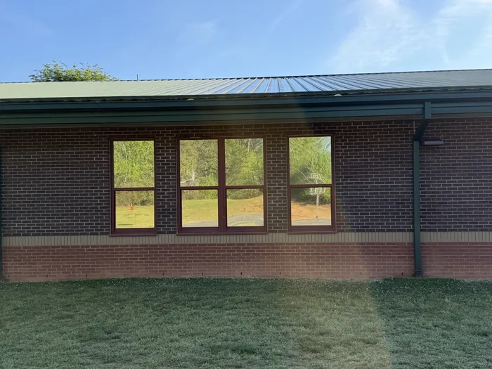 The same school windows after tinting, now reflecting the treeline and playground