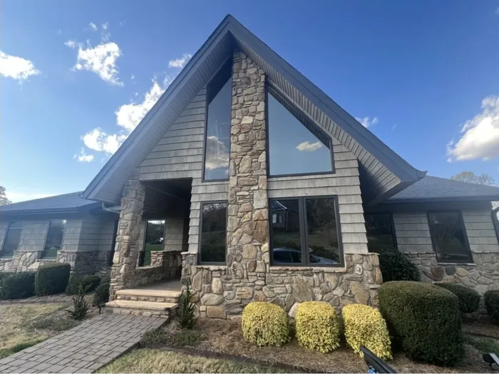 Stone A-frame house with tinted feature windows in daylight