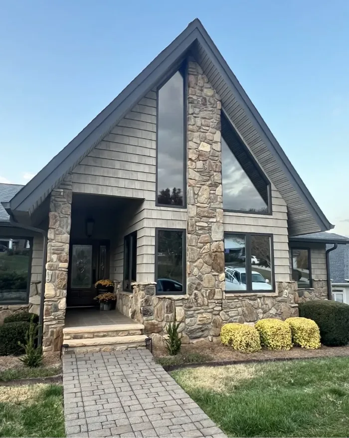 Stone A-frame house with tinted feature windows at dusk
