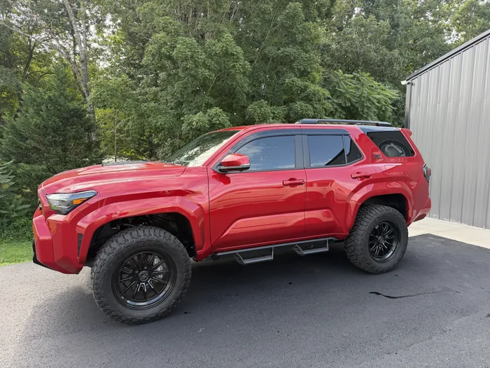 Red Toyota 4Runner TRD Sport on black wheels with tinted windows, side view